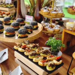 A closer view of a grazing table designed for a store launch, featuring black-bun mini burgers, savory bruschetta, and miniature tarts. We focus on variety to ensure there is a delightful bite for every guest.