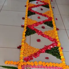 This is a floral runner or 'rangoli border' I made for a house entrance. The pattern is created with a mix of marigold petals, rose petals, and green leaves for a colorful and welcoming look.
