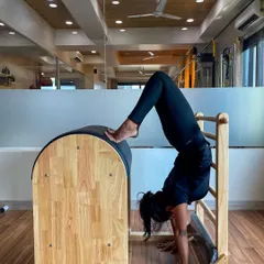 A client holding a handstand variation on the Ladder Barrel, an advanced move that builds shoulder stability and core power.