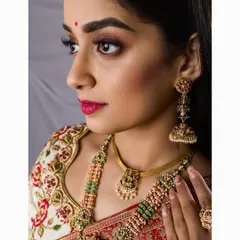 A close-up profile of the bride, highlighting her flawless makeup, detailed jewelry, and the rich colors of her traditional attire.