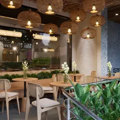 Stepping into the semi-outdoor seating area, we created a peaceful retreat. We used woven rattan pendant lights and light wood furniture to establish a warm, eco-elegant feel. The abundant greenery acts as a natural separator, offering guests a sense of privacy and calm.