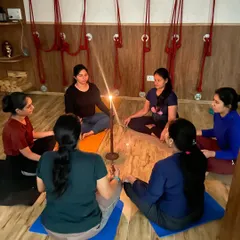 A group of women practitioners engage in Tratak meditation. The shared focus on the single flame creates a powerful, collective energy of stillness and concentration in the studio.