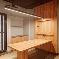 Functionality meets style with this custom-designed wooden table and integrated wall unit. The sleek, linear pendant light illuminates the workspace, demonstrating our focus on creating practical yet aesthetically pleasing furniture solutions for modern offices.