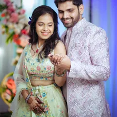A candid shot of the newly engaged couple sharing a happy moment. The groom holds the bride's hand, and their smiles show their genuine excitement and affection.