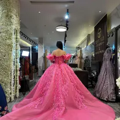 Another angle of the pink ball gown's train in the studio. The corset back and off-shoulder ruffled sleeves are visible, showcasing the craftsmanship.
