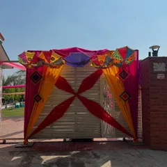 A festive gate decoration for an outdoor event. I used colorful drapes and Rajasthani umbrellas to create a vibrant and welcoming entrance for a Mehndi or Holi party.
