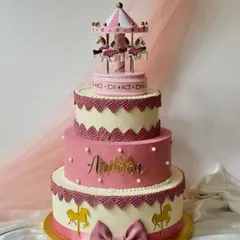 Another view of the stunning three-tiered carousel cake, personalized with the name 'Aneka'. The intricate lacework and golden details make it a true showstopper.
