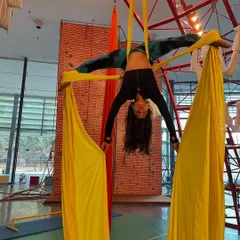 A student performs an inverted split, holding the yellow silks for support. This pose is a fantastic goal for building flexibility and upper body strength.