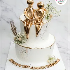 This two-tiered anniversary cake is a symbol of timeless love. We topped it with an abstract golden couple figurine and delicate baby's breath for a modern and elegant celebration of a first anniversary.