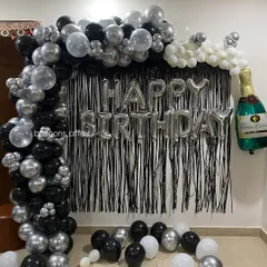 A full view of the black, white, and silver birthday backdrop, complete with a fun champagne bottle foil balloon.