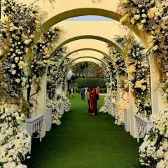 An ethereal floral archway created for an elegant day wedding. We used a dense arrangement of white and cream flowers to craft an enchanting and romantic passage for guests at Amaara Farms.