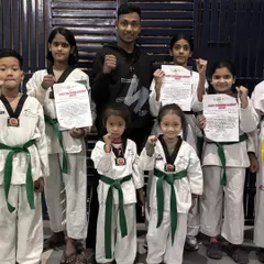 Our champions with their fists up, celebrating their new belts. This picture captures the excitement and sense of accomplishment after a successful belt test.