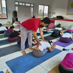 During our Rishikesh retreat, our instructor provides a hands-on assist in Paschimottanasana (Seated Forward Bend) to help a student release her lower back and deepen the fold.