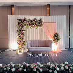 This modern and minimalist engagement stage features an asymmetrical floral arch and a simple draped backdrop. The clean lines and pastel color palette create a chic and contemporary setting for the couple.