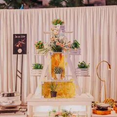 A decorative food station setup. We used a white ladder shelf adorned with flowers and greenery to create a charming, rustic display area next to the main buffet.