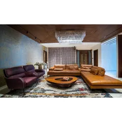 I often mix textures to create a statement. In this living room, a textured blue accent wall and a grand crystal jhoomar contrast beautifully with the warm leather sofa and wooden ceiling, creating a space that feels both grand and grounded.