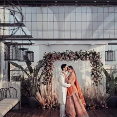A stunning wide-angle portrait of the couple on a rooftop venue overlooking the city. This shot captures both their intimate moment and the grand scale of their urban wedding.