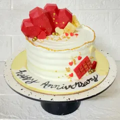 When two hearts meet. This butterscotch anniversary cake is topped with geometric chocolate hearts and decorated with edible gold dust for a modern romantic feel.