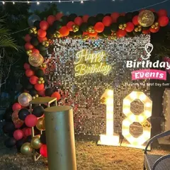 An 18th birthday setup that makes a statement. We used a silver sequin wall with a red, black, and gold balloon arch and matching marquee numbers for a bold and dramatic look.