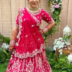 A full-length shot of this beautiful bride in her vibrant red lehenga. The makeup is balanced to stand out against the intricate outfit and the lush green background, creating a picture-perfect moment.