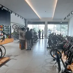 The interior of 'The Bicycle Studio', designed for an optimal customer experience. The layout is open and well-lit with track lighting, featuring clean display stands and organized product sections to make browsing easy and enjoyable.