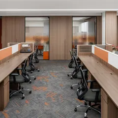 Workstations at the TajSATS office are arranged centrally with cabins along the perimeter, a layout proven effective in our previous projects. The design incorporates a consistent rust orange accent color and provides ample desk space for a comfortable work environment.