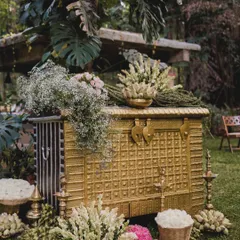 An antique gold-finished chest serves as a stunning decorative piece, overflowing with tuberose and baby's breath. This element combines vintage charm with floral elegance, creating a beautiful focal point in the garden setting.