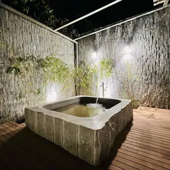 The feature is fully functional, with a discreet water inlet that creates a gentle flow, enhancing the sense of peace and tranquility. The surrounding wooden deck and stone walls complete the authentic Japanese garden aesthetic.