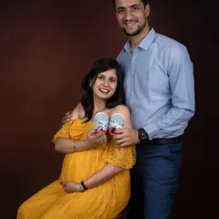 A happy couple showing off the first pair of baby shoes. It's a classic prop that symbolizes the new journey they are about to begin.