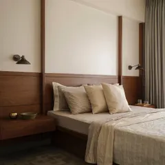 This bedroom in Apartment 1005 features a custom wood-paneled wall that integrates the headboard and floating nightstands. The design creates a warm, cohesive, and architectural element that grounds the room in natural materials.