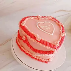 A stunning vintage heart-shaped cake with intricate, old-school piping in shades of pink and red. This style is very much in vogue and creates a beautiful, romantic centerpiece.