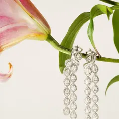 A pair of magnificent cascading diamond earrings hangs delicately from a lily stem. This creative composition emphasizes the jewellery's elegance and connects it with natural beauty.