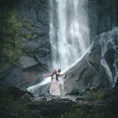 A majestic shot of a couple standing before a powerful waterfall. We seek out dramatic natural landscapes around Bangalore to create truly epic pre-wedding photographs.