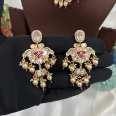 The matching earrings for the 'Noor Nazaakat' set, held to show their design.