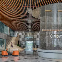 The grand, double-height lobby of the Aurobindo Orbit commercial building in Hyderabad. We used a rich palette of marble and wood, with a custom-designed metal jali screen, to create a sense of arrival that blends commercial sophistication with regional context. The space is designed to feel both impressive and welcoming, setting a new standard for corporate interiors.