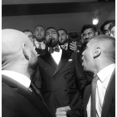 A high-energy, candid black and white shot of the groom celebrating with his friends, capturing the raw emotion and excitement of the party.