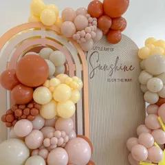 A "Little Ray of Sunshine" is on the way. This baby shower theme uses warm, earthy tones and arched backdrops to create a joyful and welcoming atmosphere for the celebration.