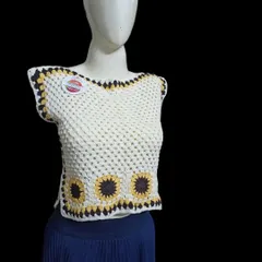 Inspired by sunflowers, this sleeveless top features a line of sunflower granny squares along the bottom. The simple white top with a pop of yellow and brown makes it a cheerful and fun piece to wear.