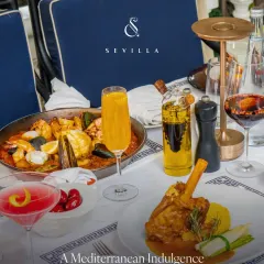 A Mediterranean indulgence spread across the table. You can see our signature Paella and lamb shank alongside vibrant cocktails, representing the feast we love to share with our guests.