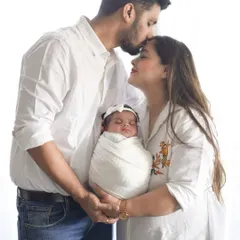 A beautiful family portrait with a newborn. The coordinated white outfits create a bright, airy, and pure look, while the loving poses show the deep connection of the new family.