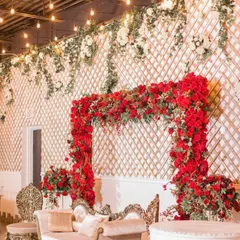 For this stage, I created a bold statement with a large arch made of fresh red roses against a white lattice wall. The top of the wall is decorated with hanging white flowers and greenery for a garden-like feel.