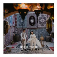 A beautifully composed shot of a couple in an ethnic-themed setting, surrounded by intricate carpets and lanterns. This image has a rich, cultural, and almost regal feel.
