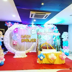 For a modern and fun baby shower, we design vibrant balloon-based decorations. This setup includes a custom crescent moon prop, balloon arches in pink, blue, and white, and cute baby-themed cutouts.