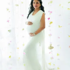 Cradling the miracle within. This mother-to-be looks like a goddess in a classic white gown, surrounded by a delicate curtain of flowers for an ethereal touch.