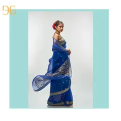 The magic of silk organza is in its weightless drape. This ethereal cerulean blue saree flows effortlessly, adorned with delicate gold zari buttis. The pallu showcases a rich floral motif, making it a piece of wearable art.