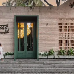 The entrance to Ishtaa restaurant sets a modern yet earthy tone with its clean brick facade and a bold green statement door. This exterior design hints at the warm, nature-inspired hospitality interior that awaits guests inside, creating a memorable first impression.