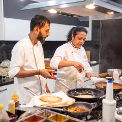 Teamwork in the kitchen. Here, two of our chefs coordinate over multiple pans on the stove, ensuring every component of the meal is cooked to perfection.