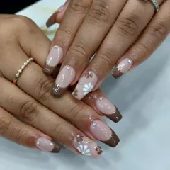 We love creating unique color combinations, like this chocolate brown French manicure. The design is elevated with hand-painted white floral details and tiny rhinestone accents.