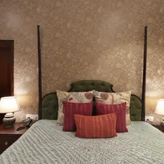 A detailed view of the custom bed, featuring a gorgeous tufted green headboard and carefully chosen accent pillows. The combination of textures and colors adds depth and a sense of bespoke luxury to the room.