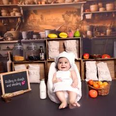 A happy smile from the star of our kitchen-themed session. I ensure the environment is fun and engaging for the baby, which helps in capturing these genuinely happy moments.